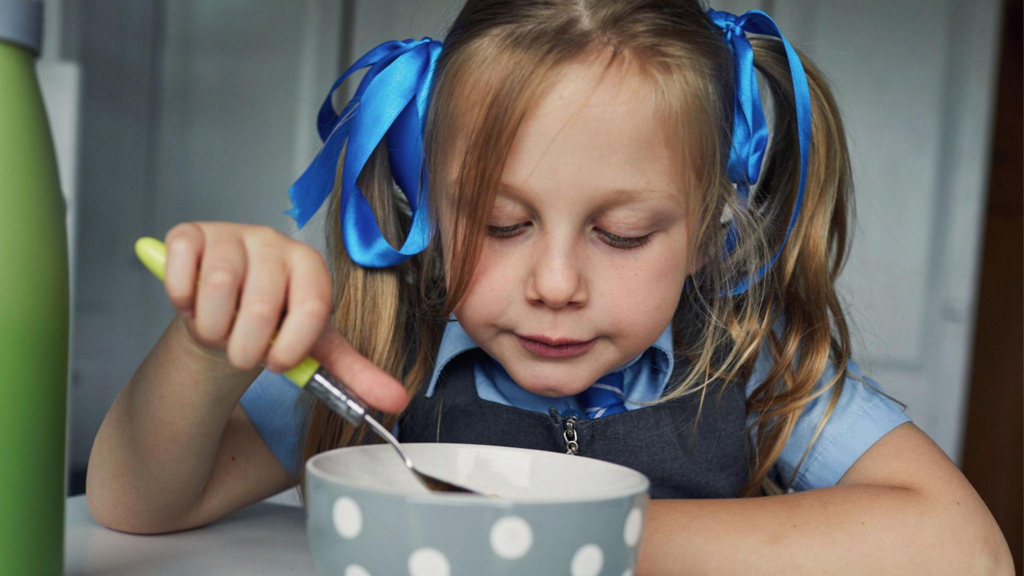 A girl eating breakfast from a bowl. 