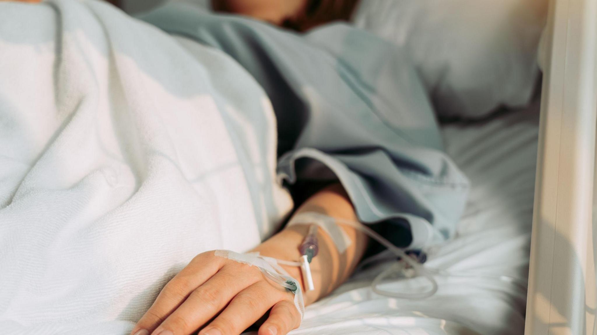 patient in hospital bed with tubes on wrist