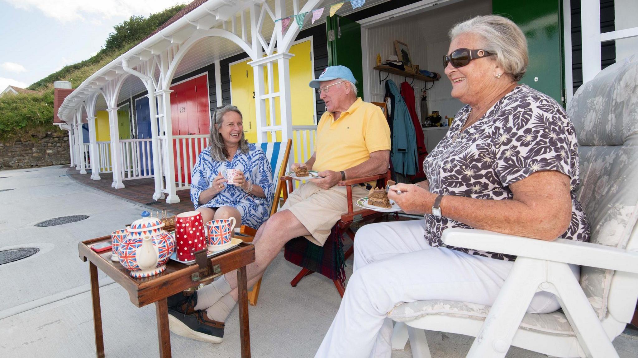 Martin and Jenny Johnson and their daughter, Lisa, drink tea outside one of the new chalets