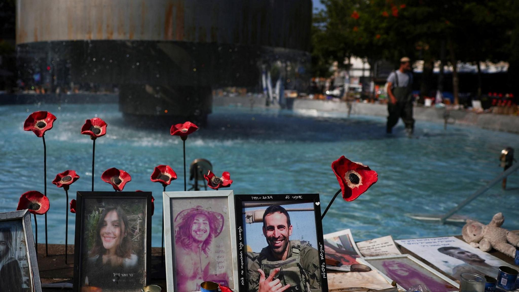 A man cleans a fountain in Tel Aviv next to photographs of Israelis taken hostage during Hamas's 7 October attacks on Israel (12 August 20240