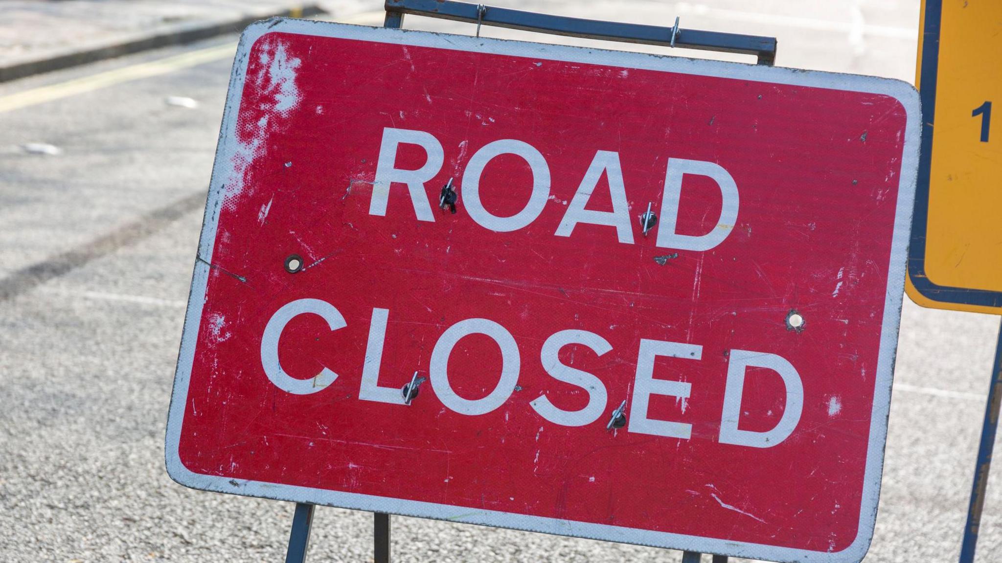 A red sign with "ROAD CLOSED" written in white capital letters.