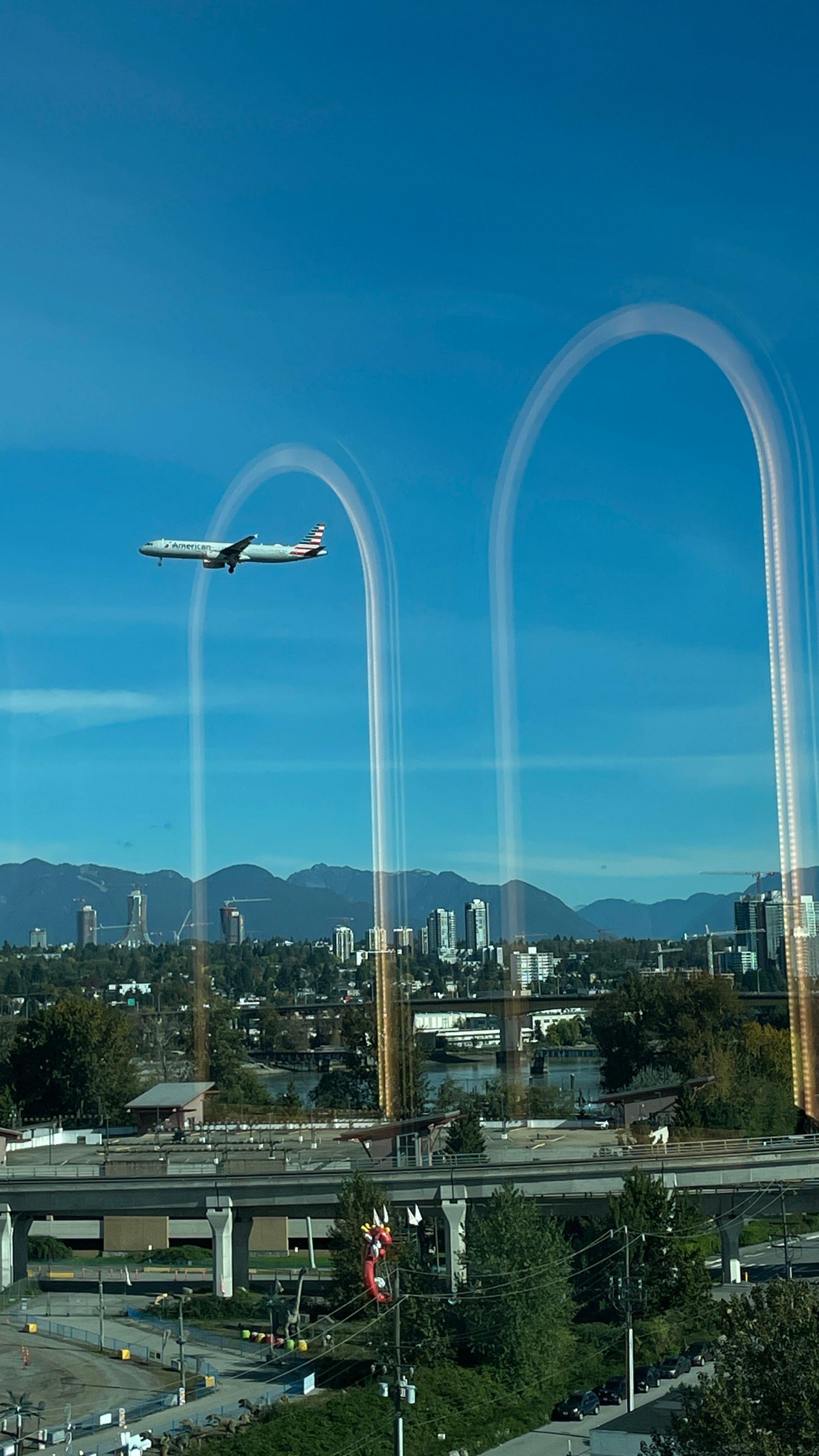 A aeroplane seems to fly through an arch reflected in a hotel window