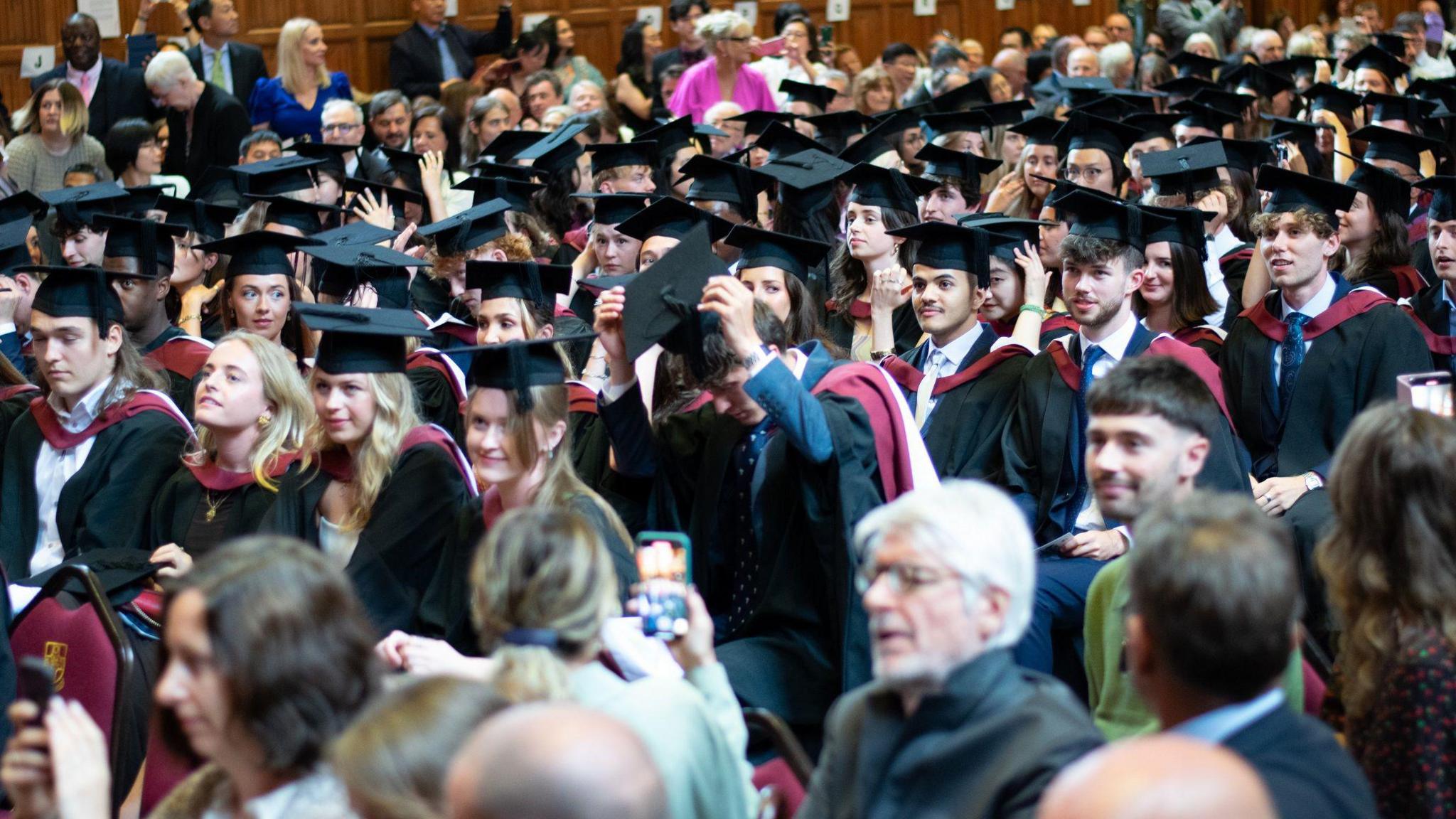 Dozens of University of Bristol students sit in the Great Hall at their graduation ceremonies with mortar boards and gowns