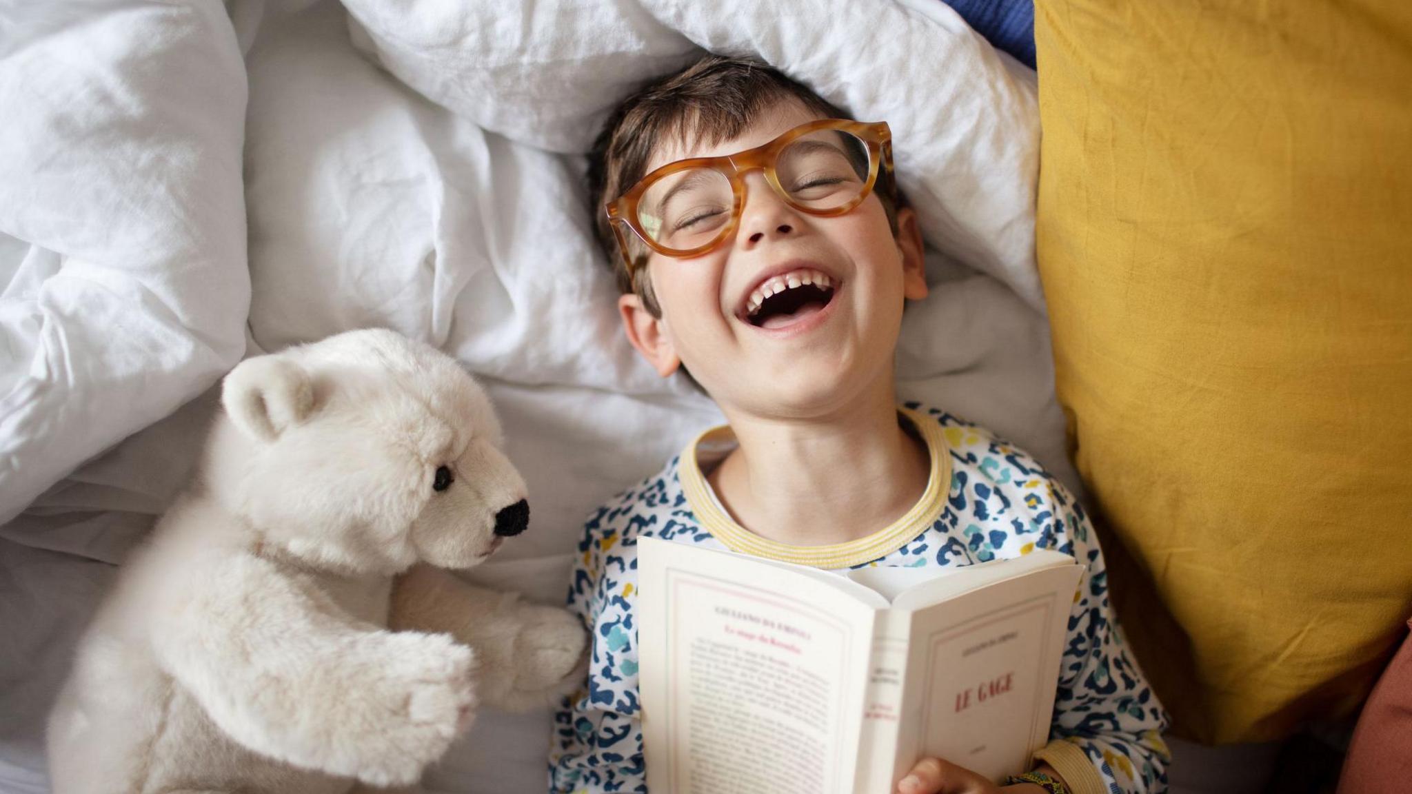 happy boy in bed reading a book