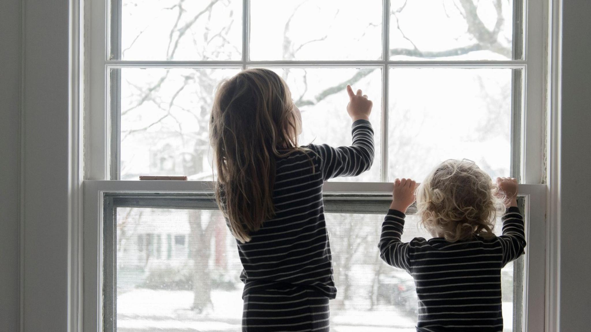 Children looking out the window to snow 