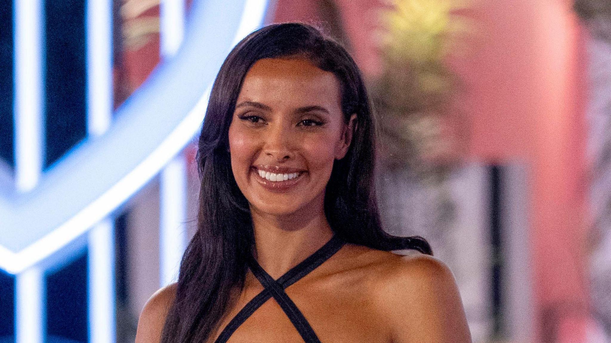 Love Island host Maya Jama wears a black strappy dress.