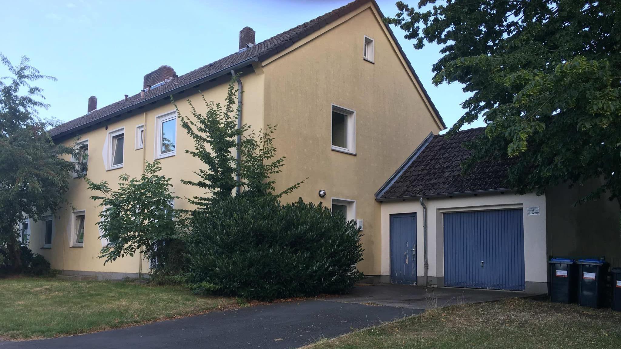 A yellow, three-bedroom home with a garage and drive.