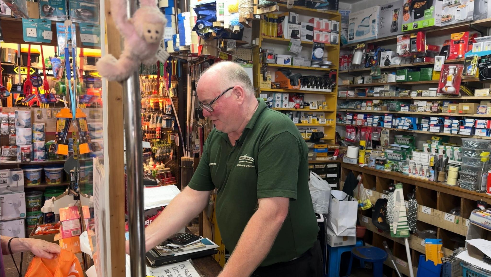 The owner of Mogfords Paul Gilliam is standing behind the counter of his shop