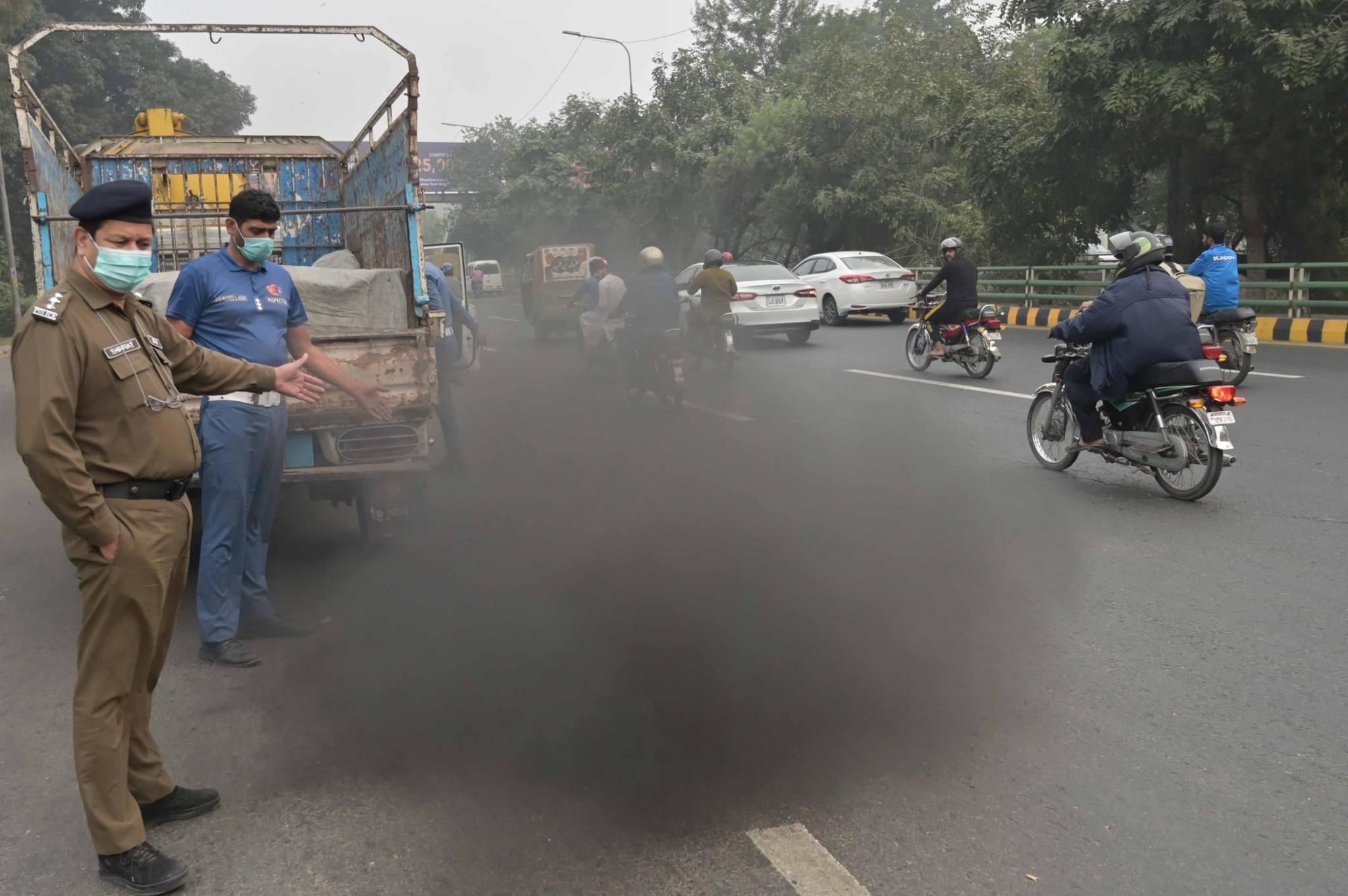 Pakistani security officials check for vehicles emitting smoke in Lahore