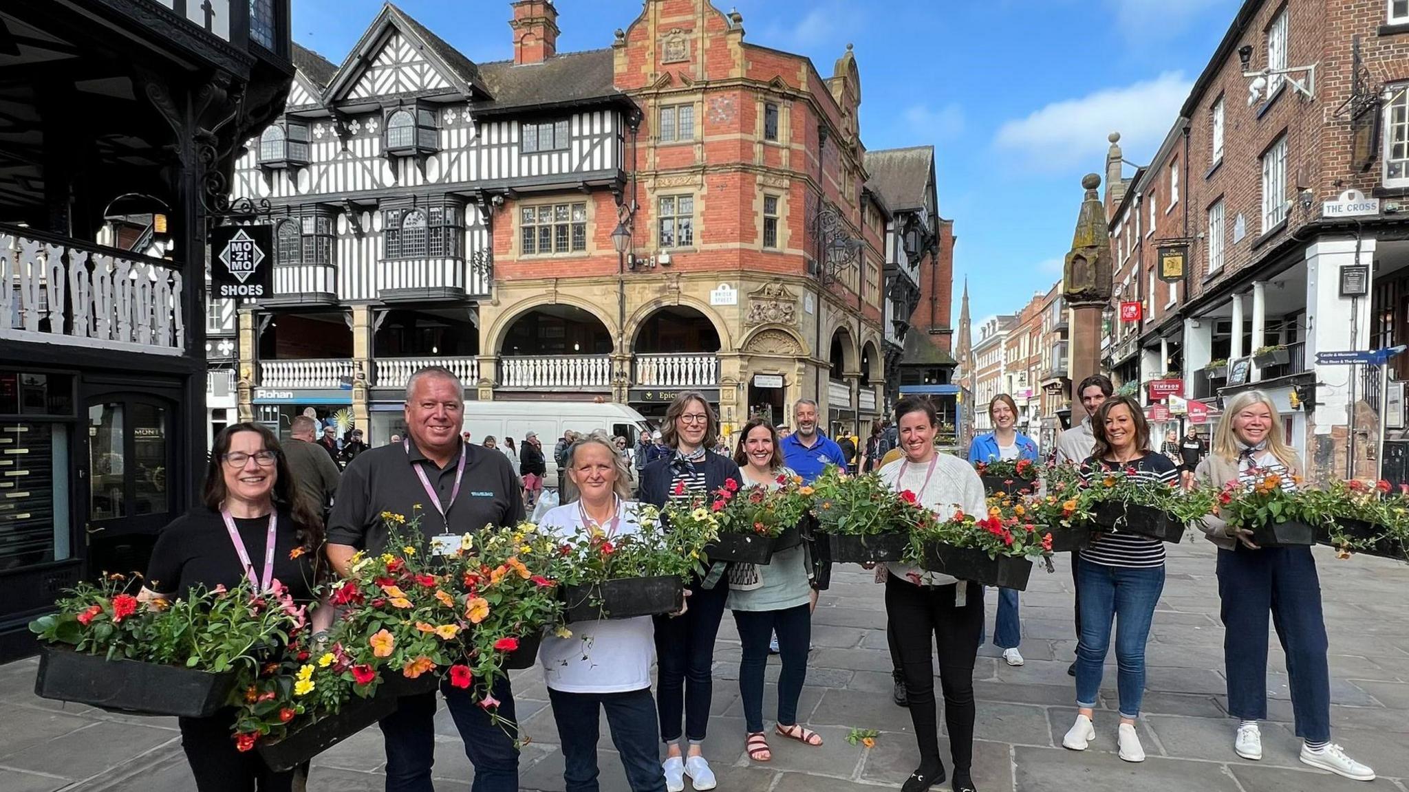 Group of people holding baskets of flowers in Chester city centre