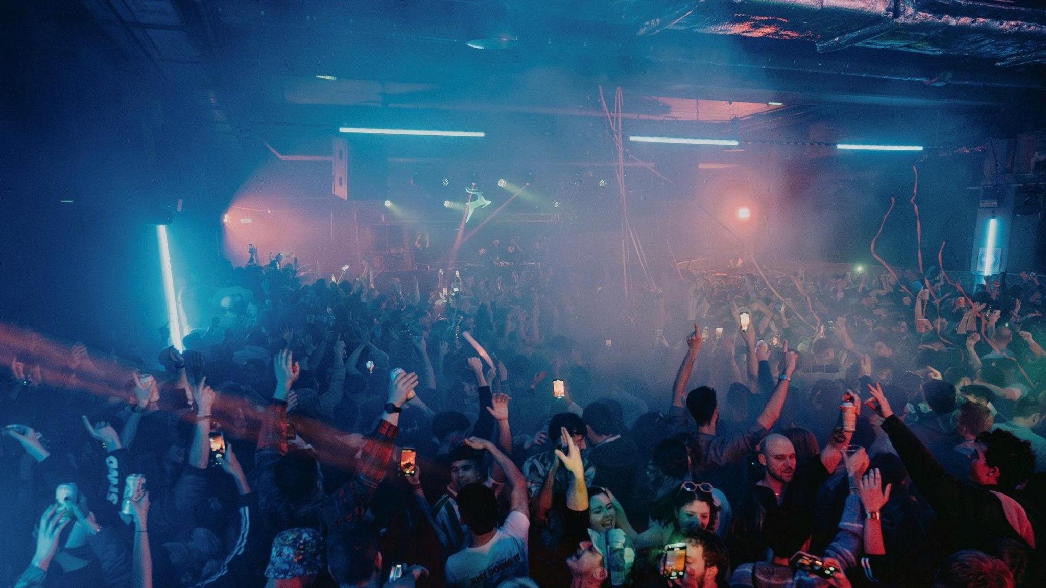 Club goers are pictured dancing to music at an underground venue.