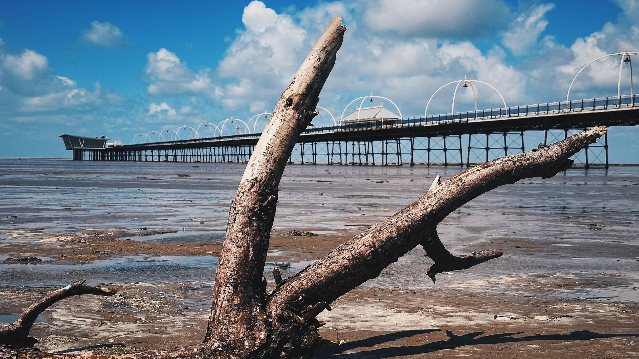 Southport pier photographed on a sunny day. It is shot from the beach, with the end of the pier on the horizon.