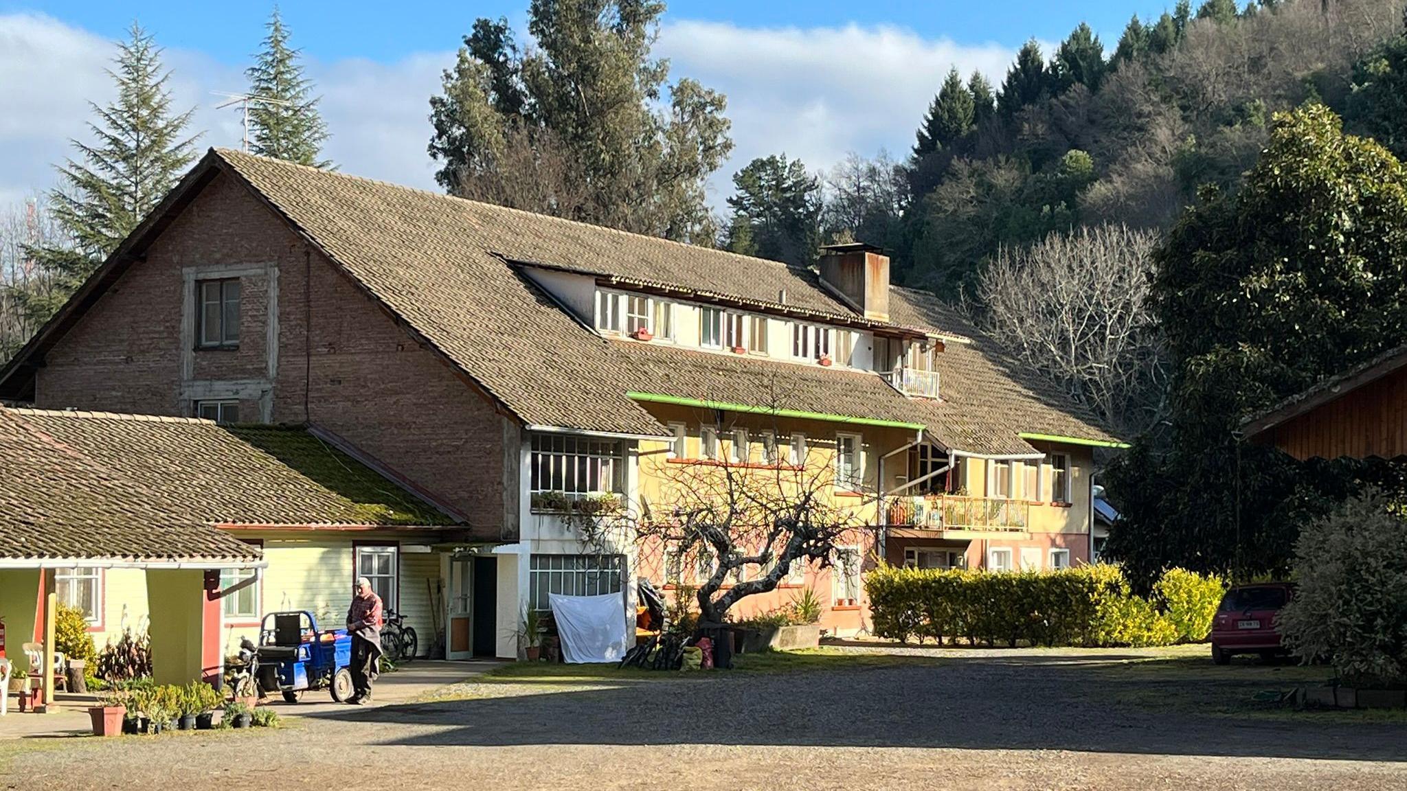 A large building can be seen surrounded by trees. Washing is hanging out to dry in front of the building. 