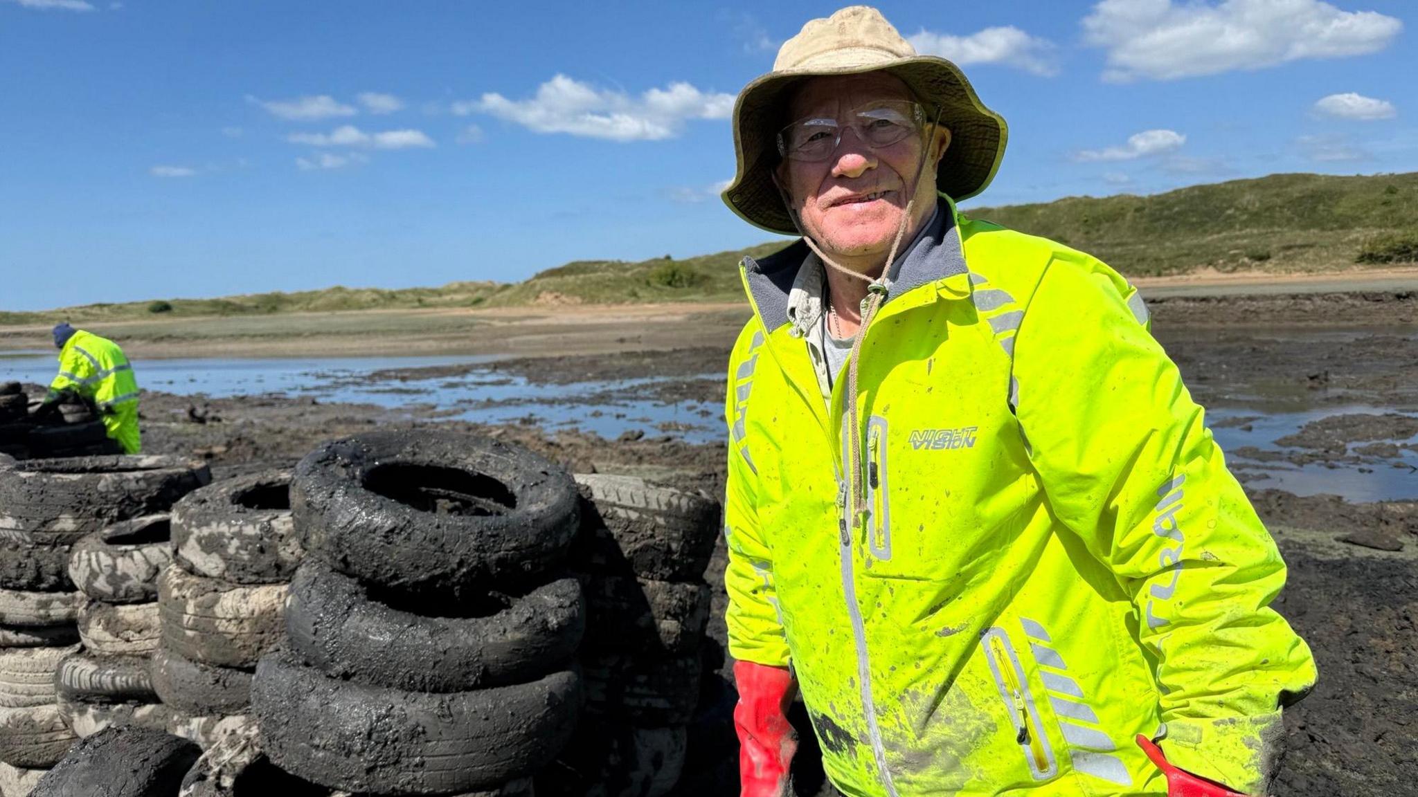 Andrew Stride, from Ogmore Angling Association wears a hi-vis jacket and is pictured next to tyres