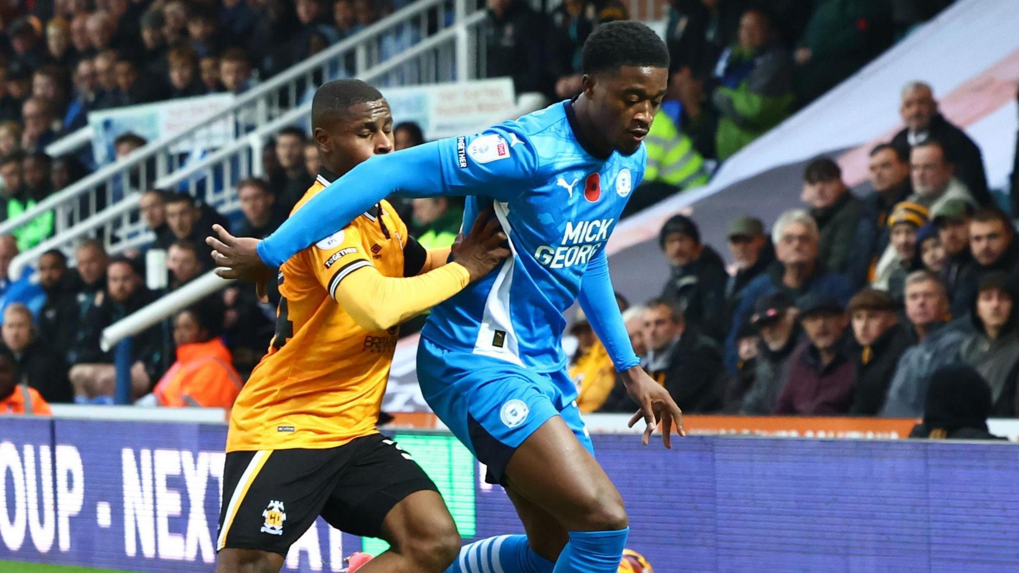 Peterborough's Kwame Poku holds off a Cambridge United defender during their derby game in League One