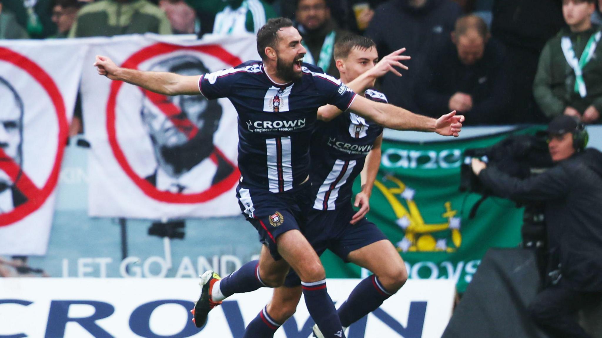 Clark Robertson celebrates in front of Celtic fans' protest banners