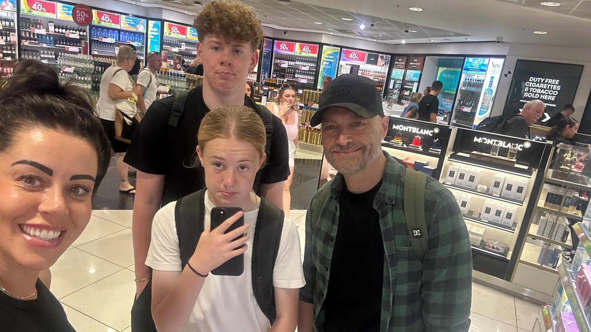 Katie Potter and family taking a selfie, they are in the duty free area of Birmingham Airport 