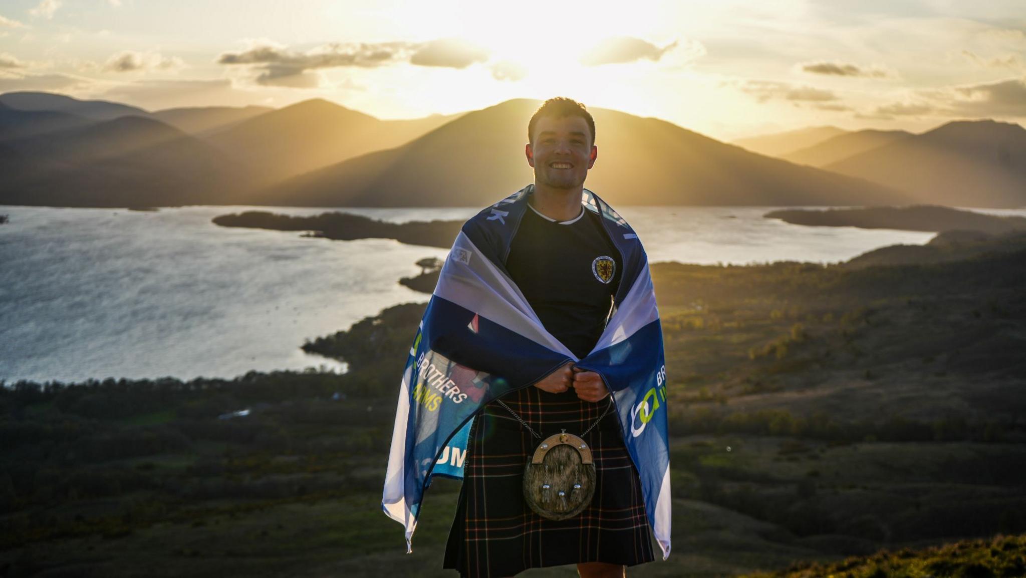 Craig Ferguson in a kilt near a loch 