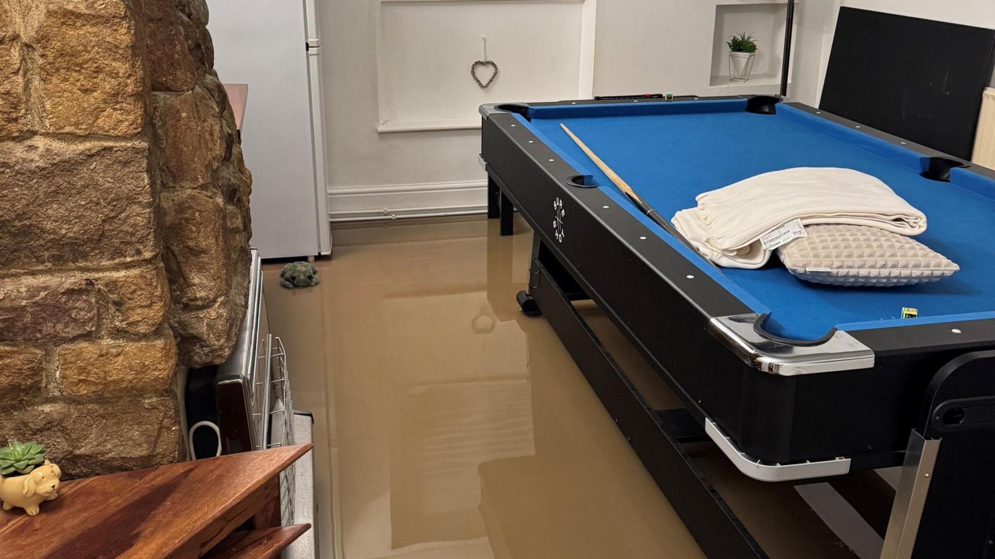 Flood water in the room of a house, with a snooker table in 