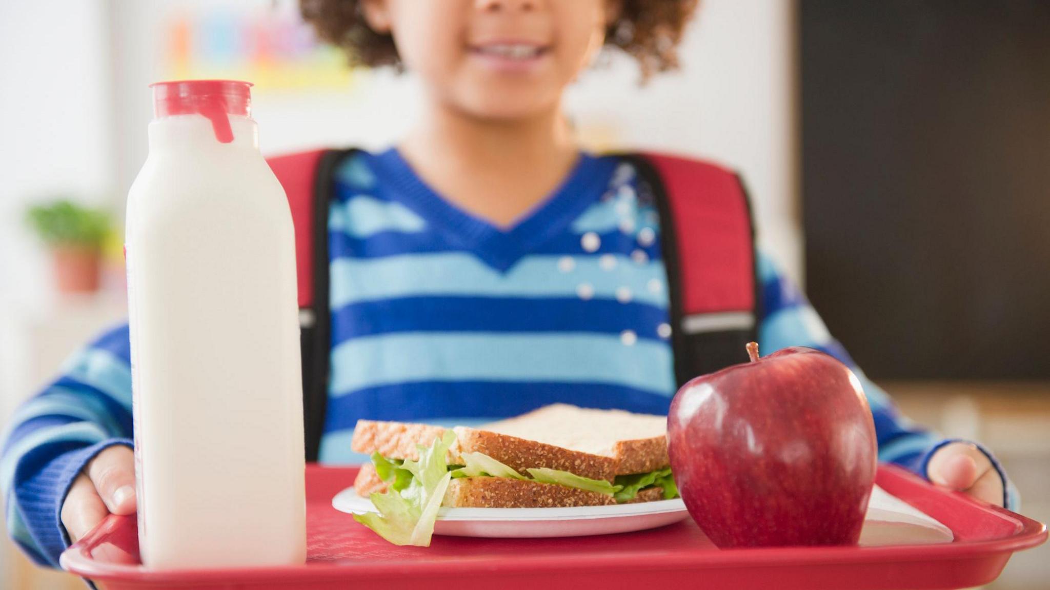 School girl holding lunch on a tray