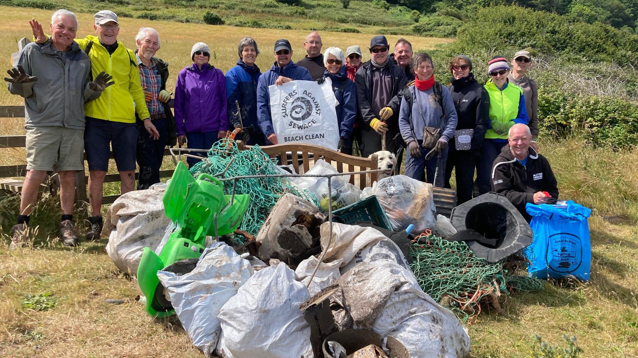 Volunteers stood in a field with a large pile of debris found on the beach