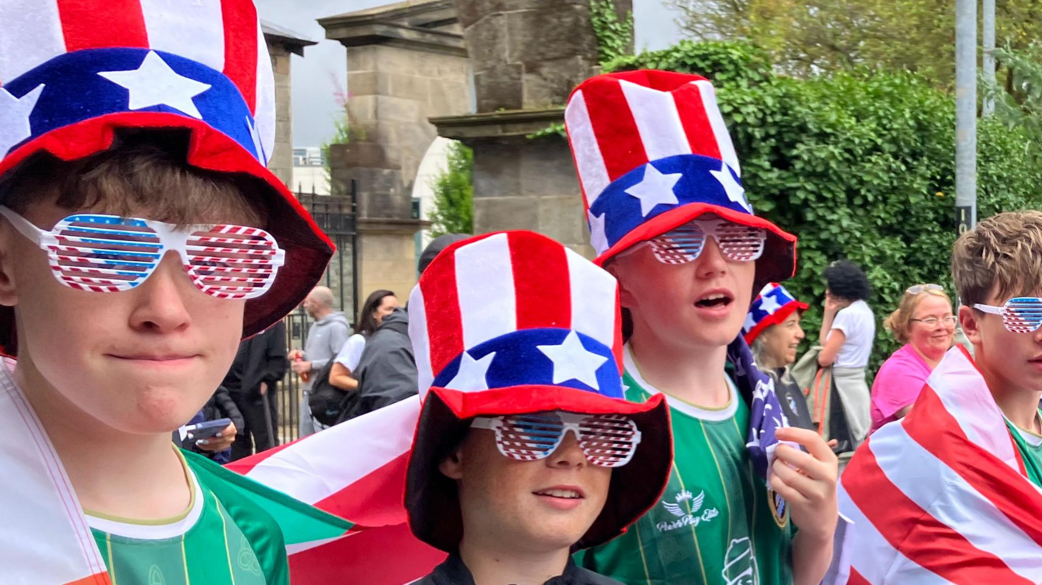 Young footballers in green shirts, carrying Stars and Stripes flags and wearing Stars and Stripes hats