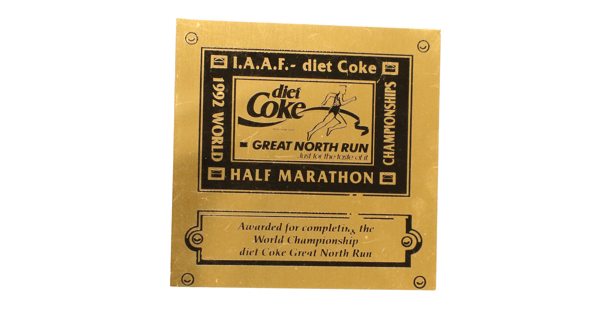 A large rectangular shaped gold medal with a black square on with writing that reads I.A.A.F- diet coke, 1992 world half marathon championships. It says awarded for completing the World Championship diet coke great north run and has a runner going through a black ribbon.