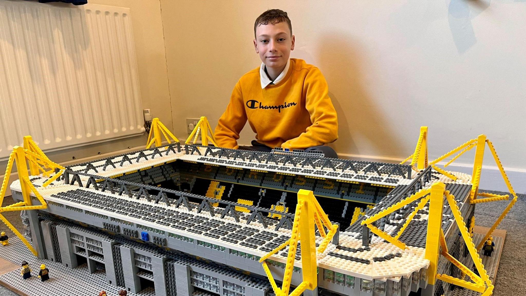 Jo Bryany sitting behind a stadium he has built out of lego.