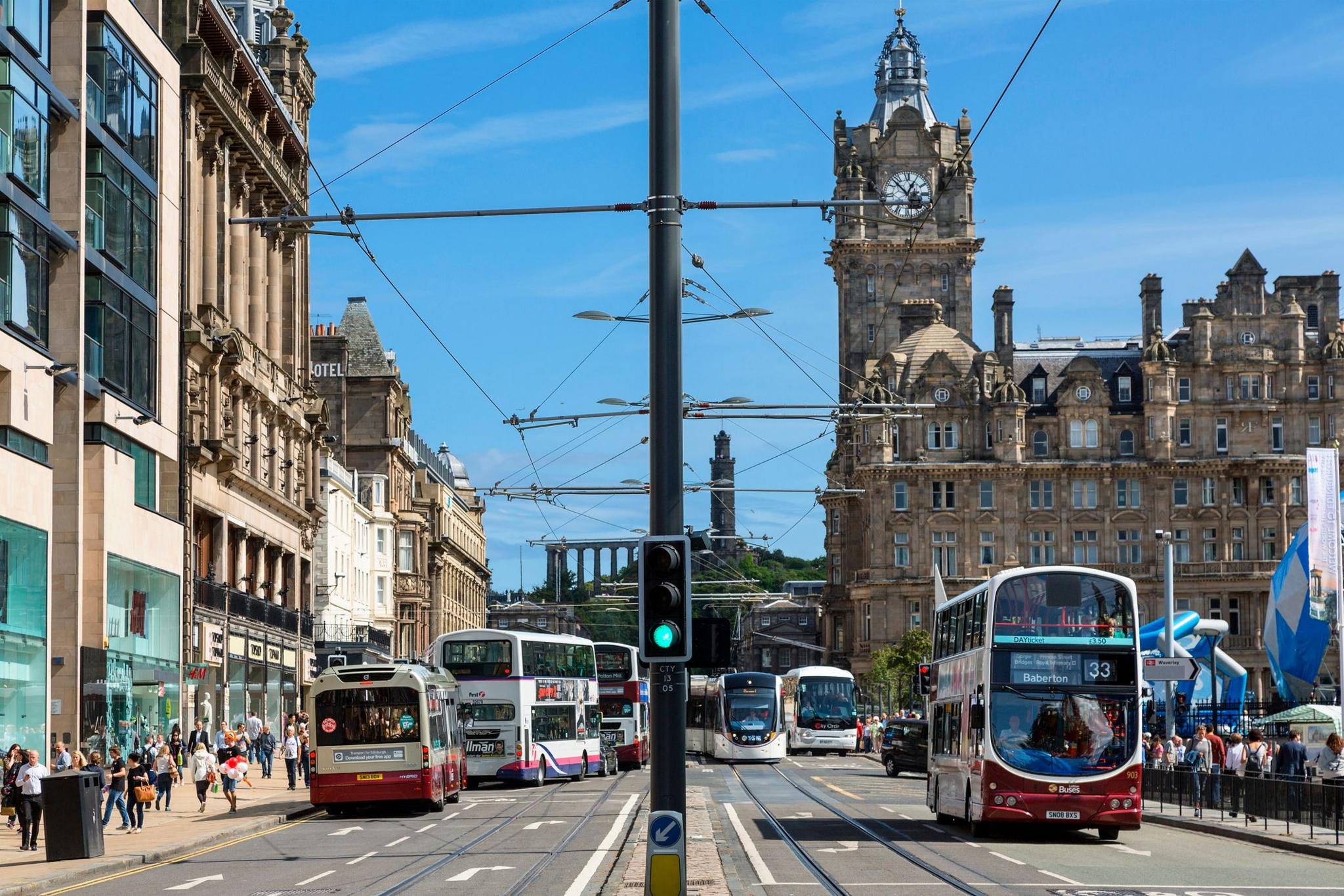 A view of the Scotsman hotel on Edinburgh's Princes Street, which has tram lines in both directions and is busy with several bus services