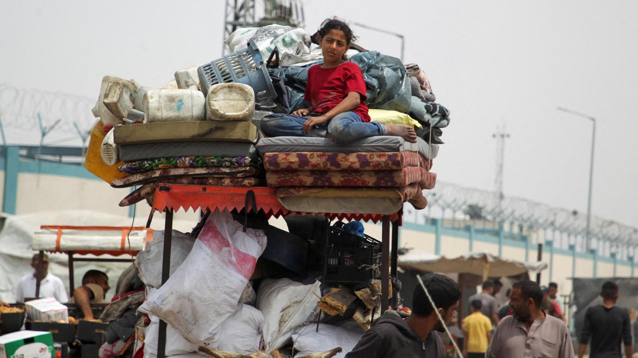 A Palestinian girl sits on top of possessions being transported by a cart in Rafah, in the southern Gaza Strip (28 May 2024) 