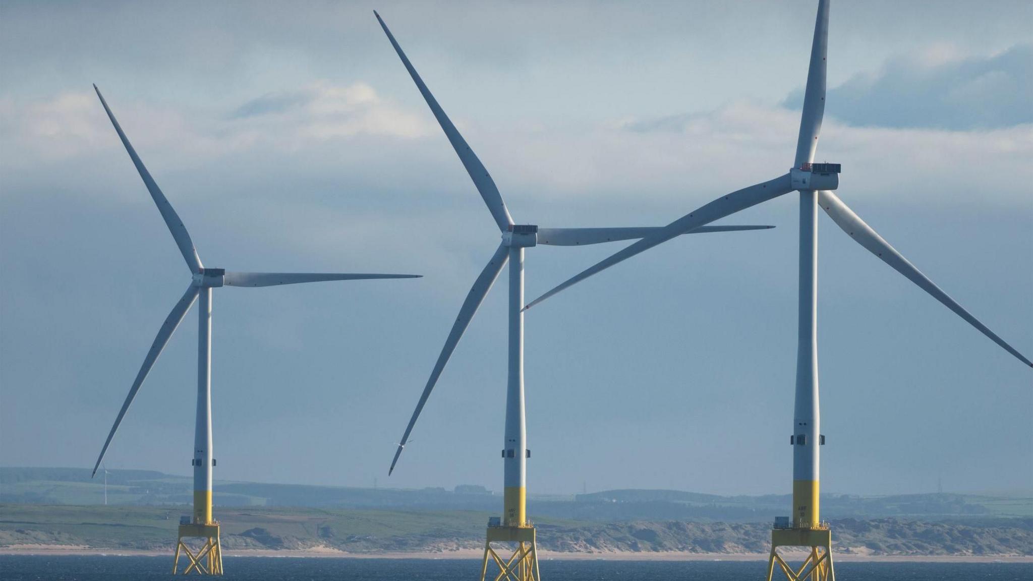 Three offshore wind turbines in the sea off the coast of the UK