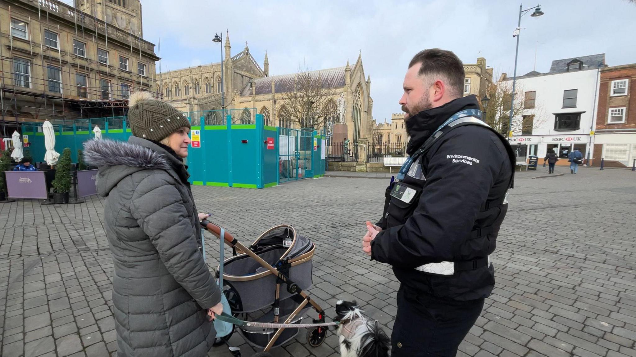 Enforcement officer Jason Washington stops a woman walking a small black and white dog.