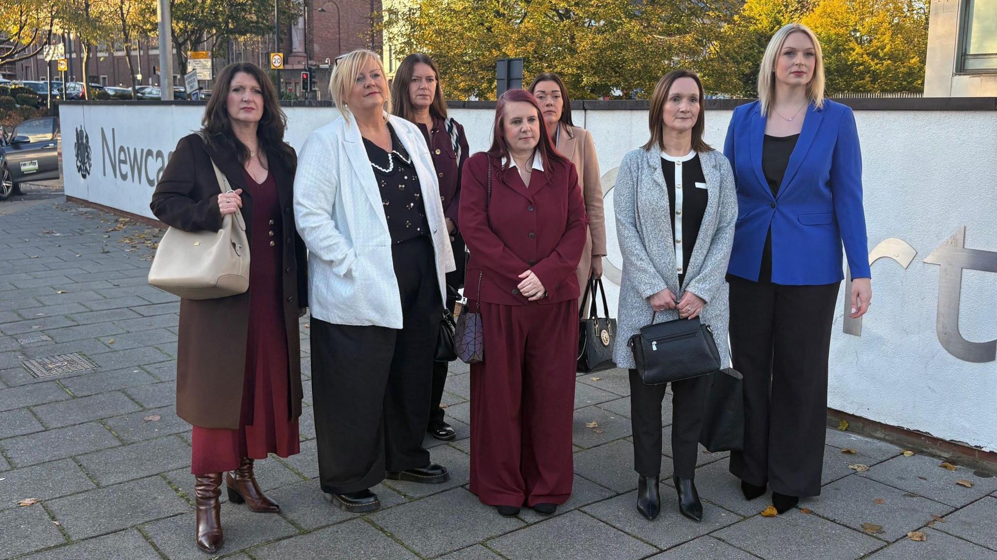 Seven nurses standing outside the tribunal centre in Newcastle. They are wearing smart outfits and serious expressions.
