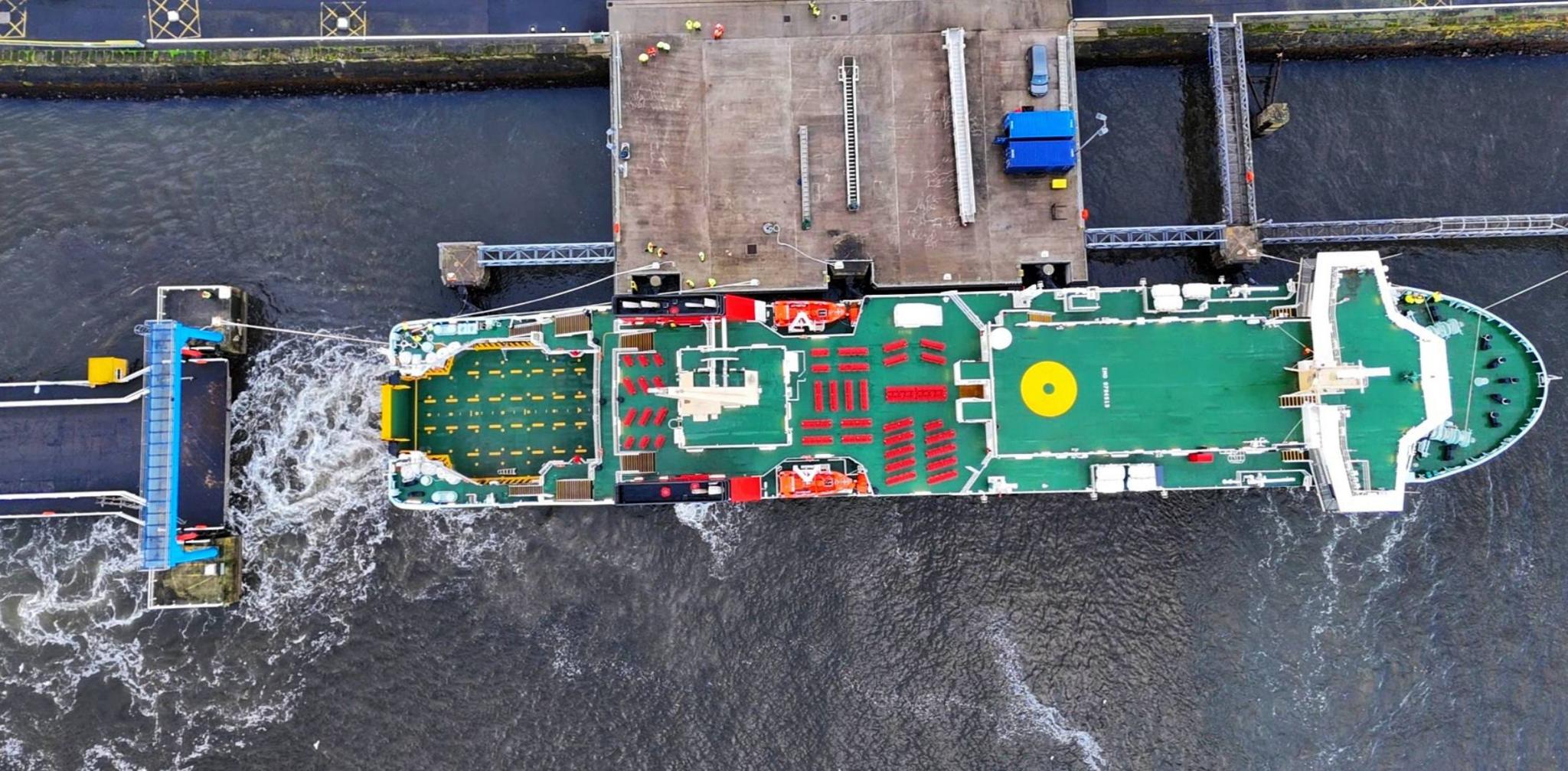 Aerial view of a large ship with green decks and red outdoor seats