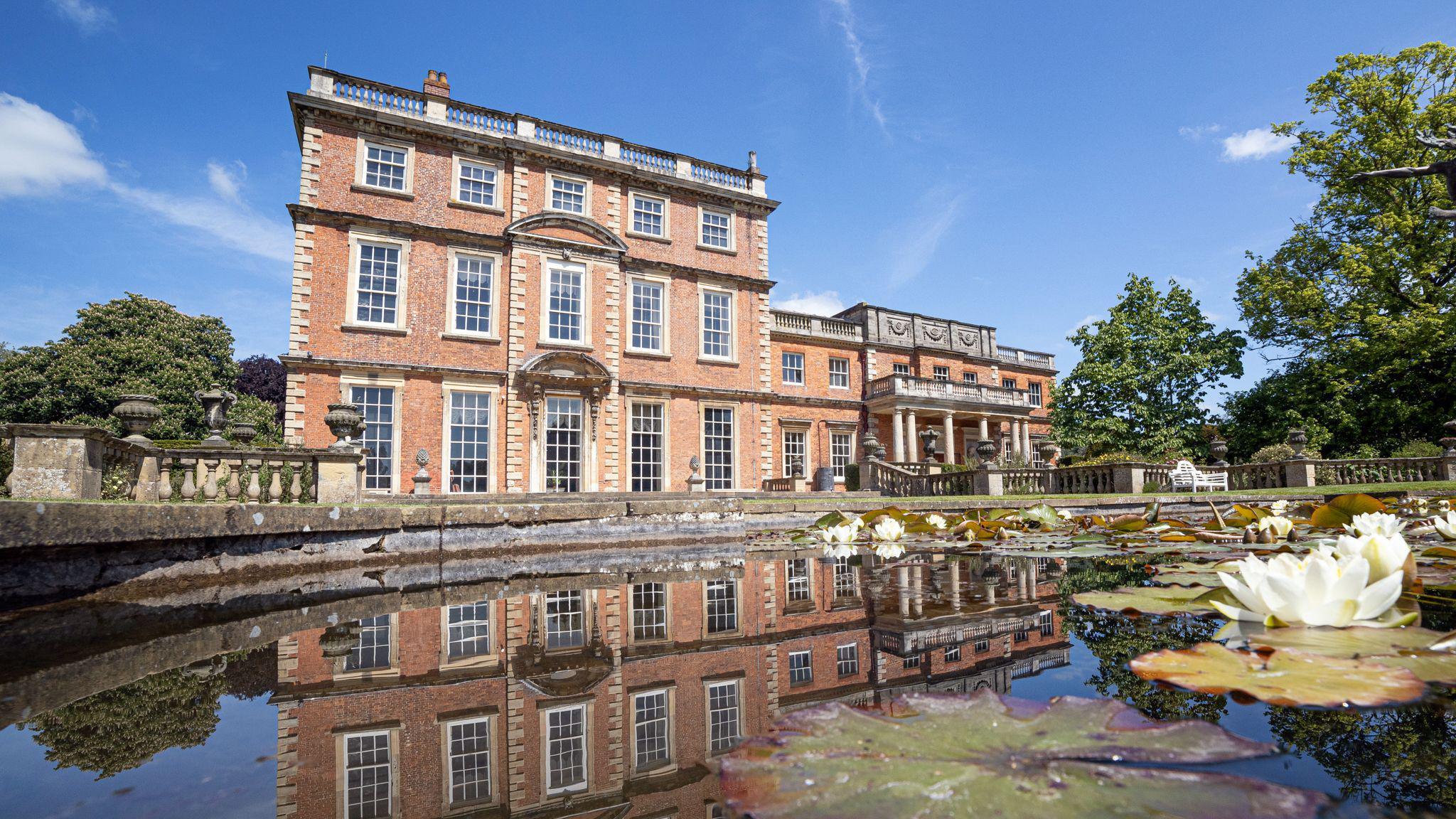 Newby Hall and pound. There are some lily pads in the pond and flowers.