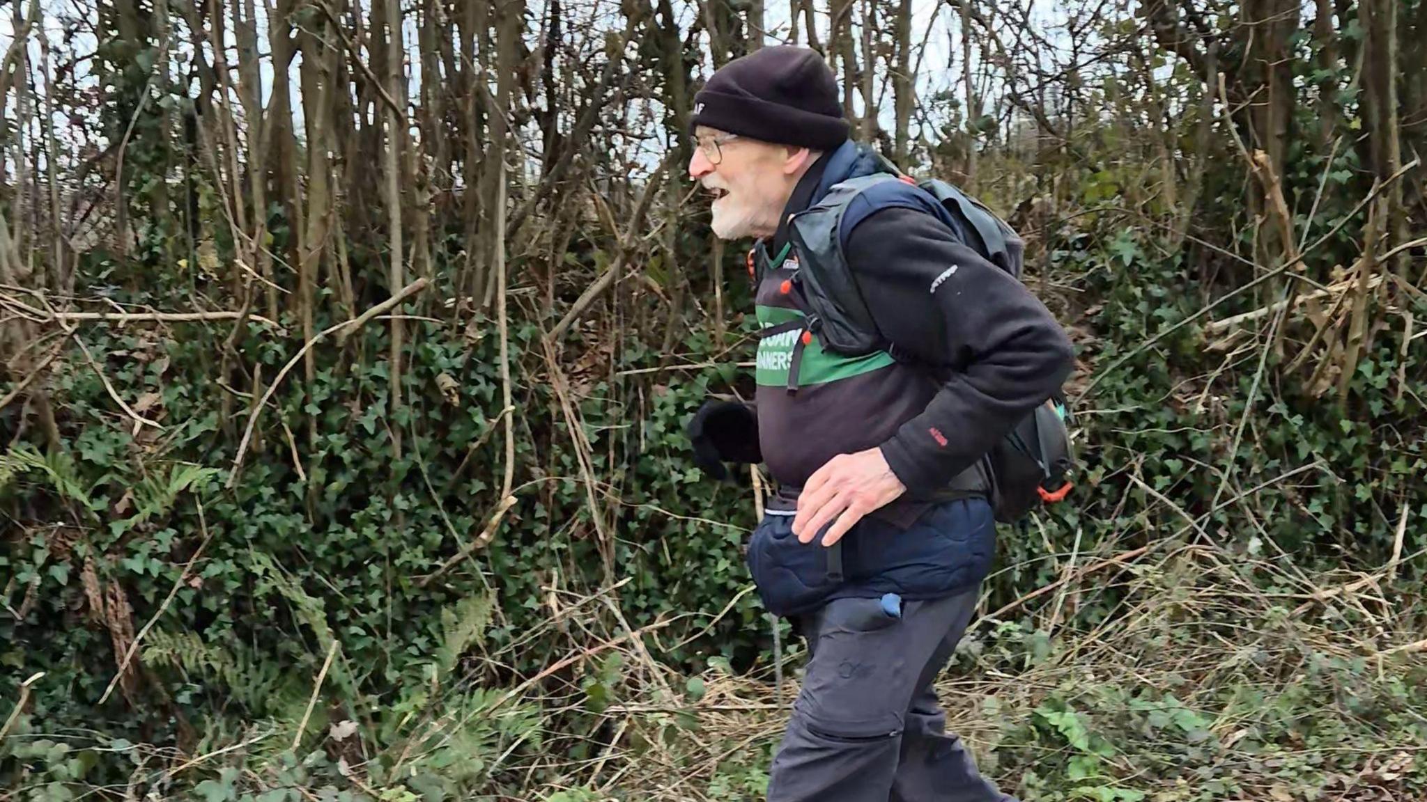 Paul Youd jogs down a country road wearing bags and winter clothes