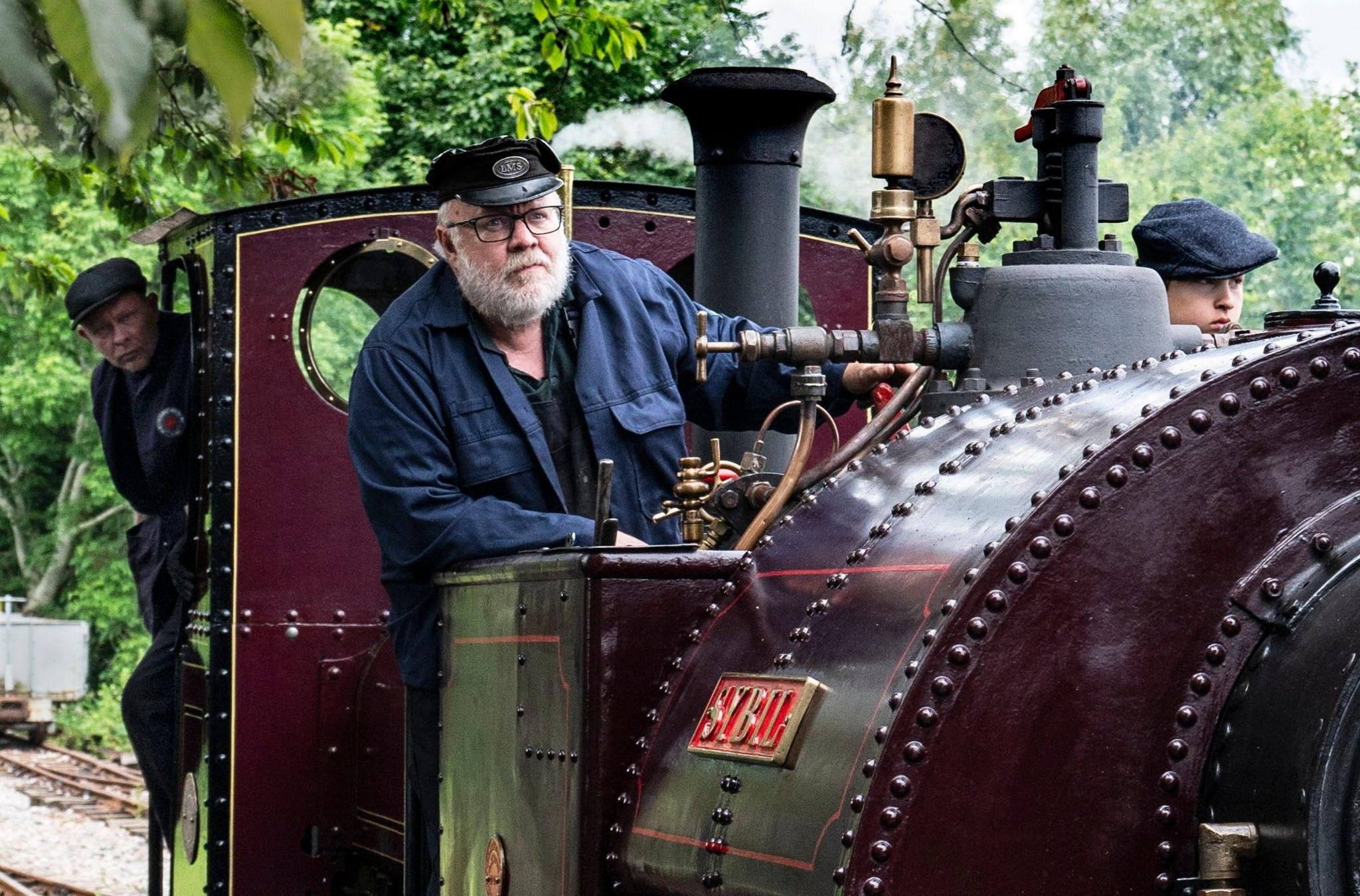 Three people drive a steam train 