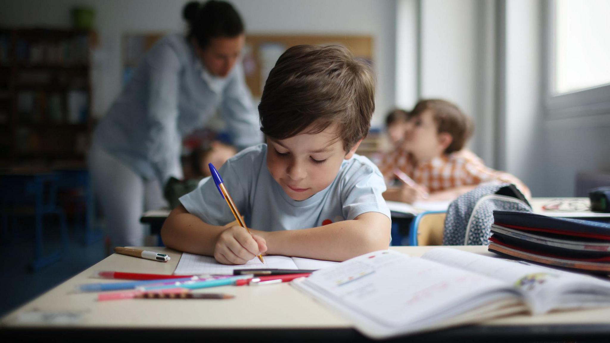 A young boy writing on paper with a pen