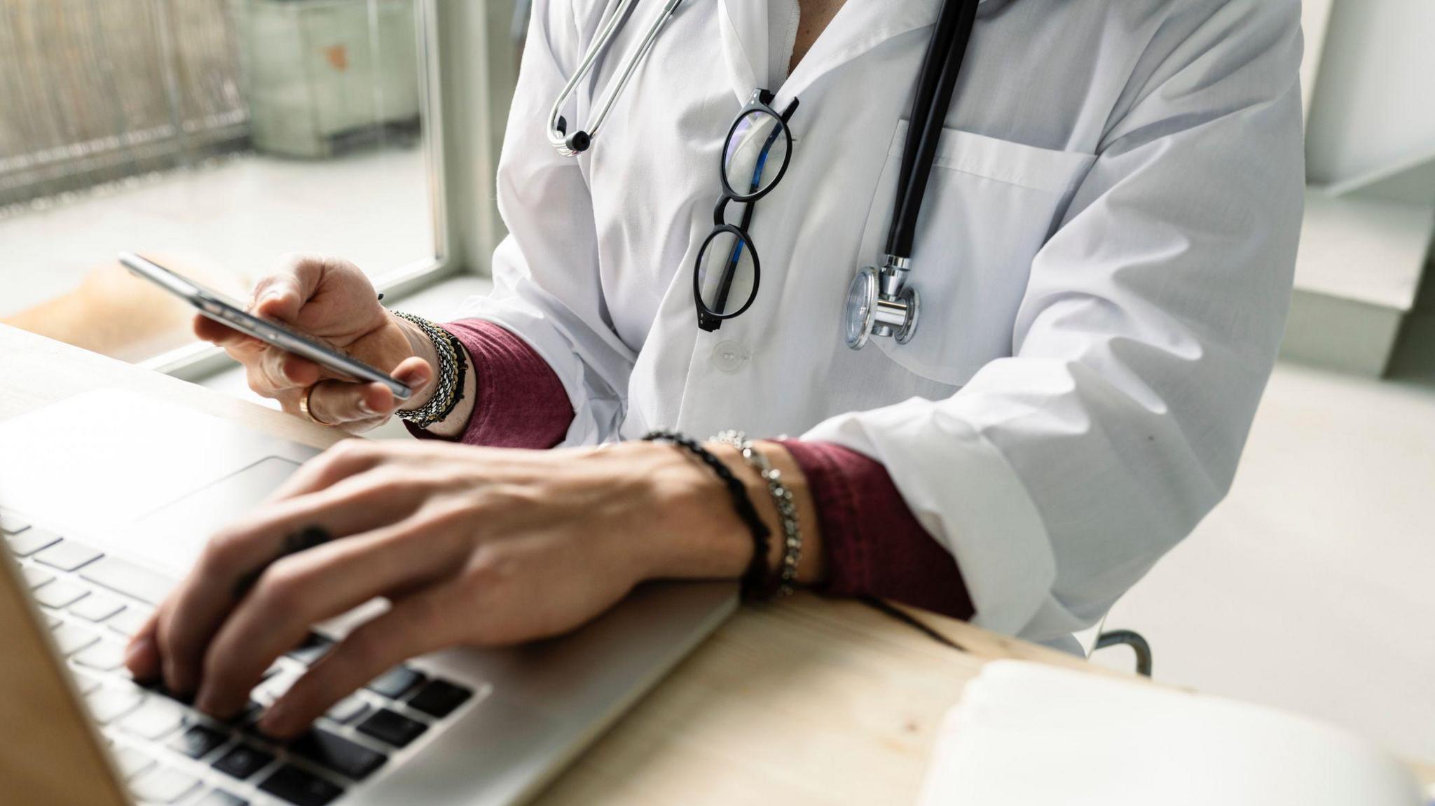 A doctor typing on a laptop