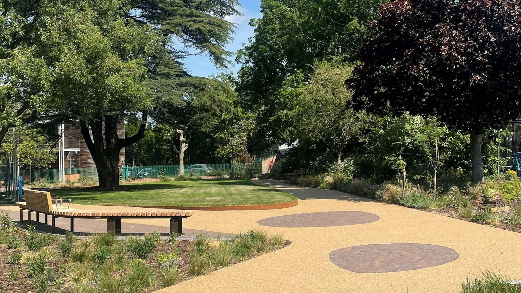 The Peace Garden has wooden benches and a pathway around a green lawn.