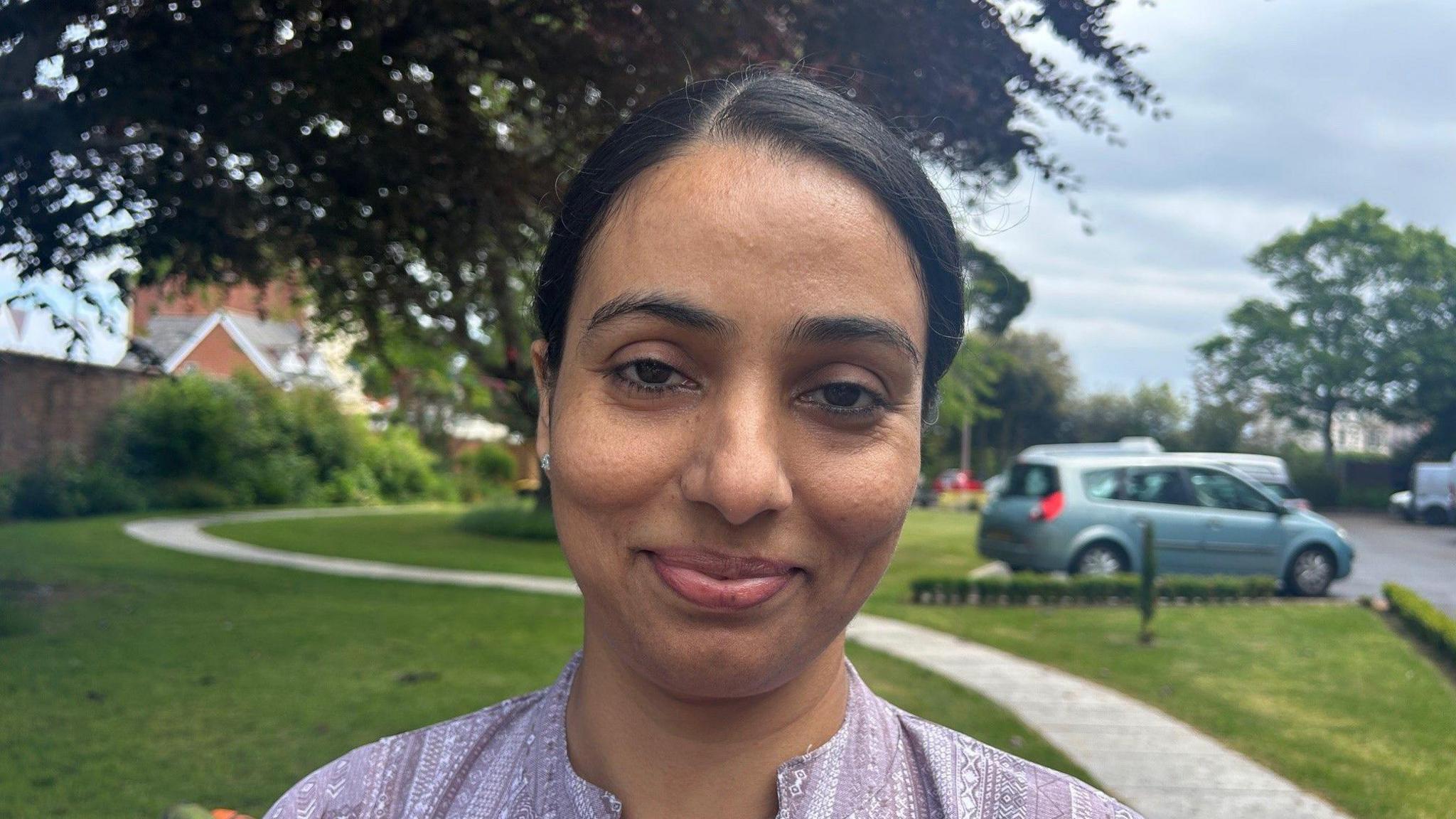 An Asian woman with a purple top smiling at the camera