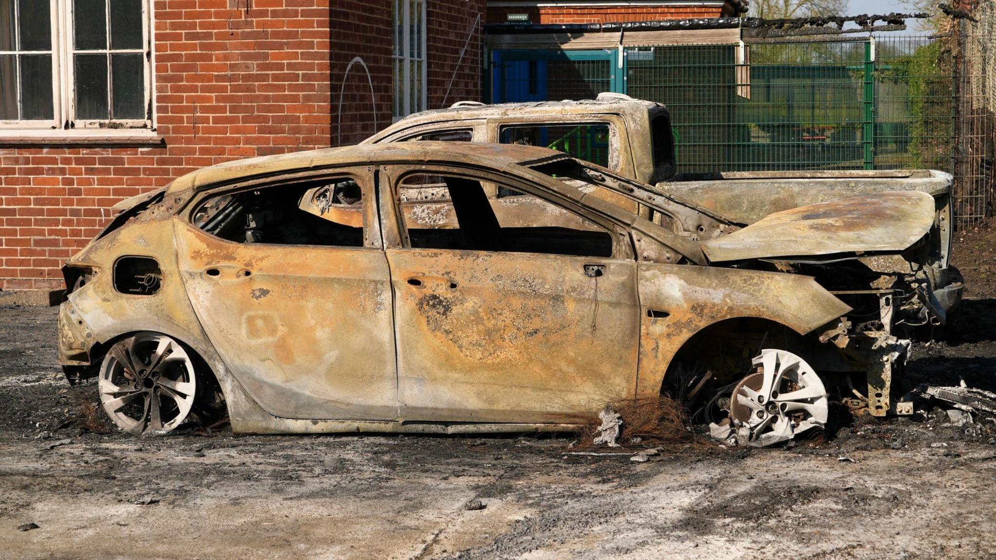 Two burnt out cars in front of the school building