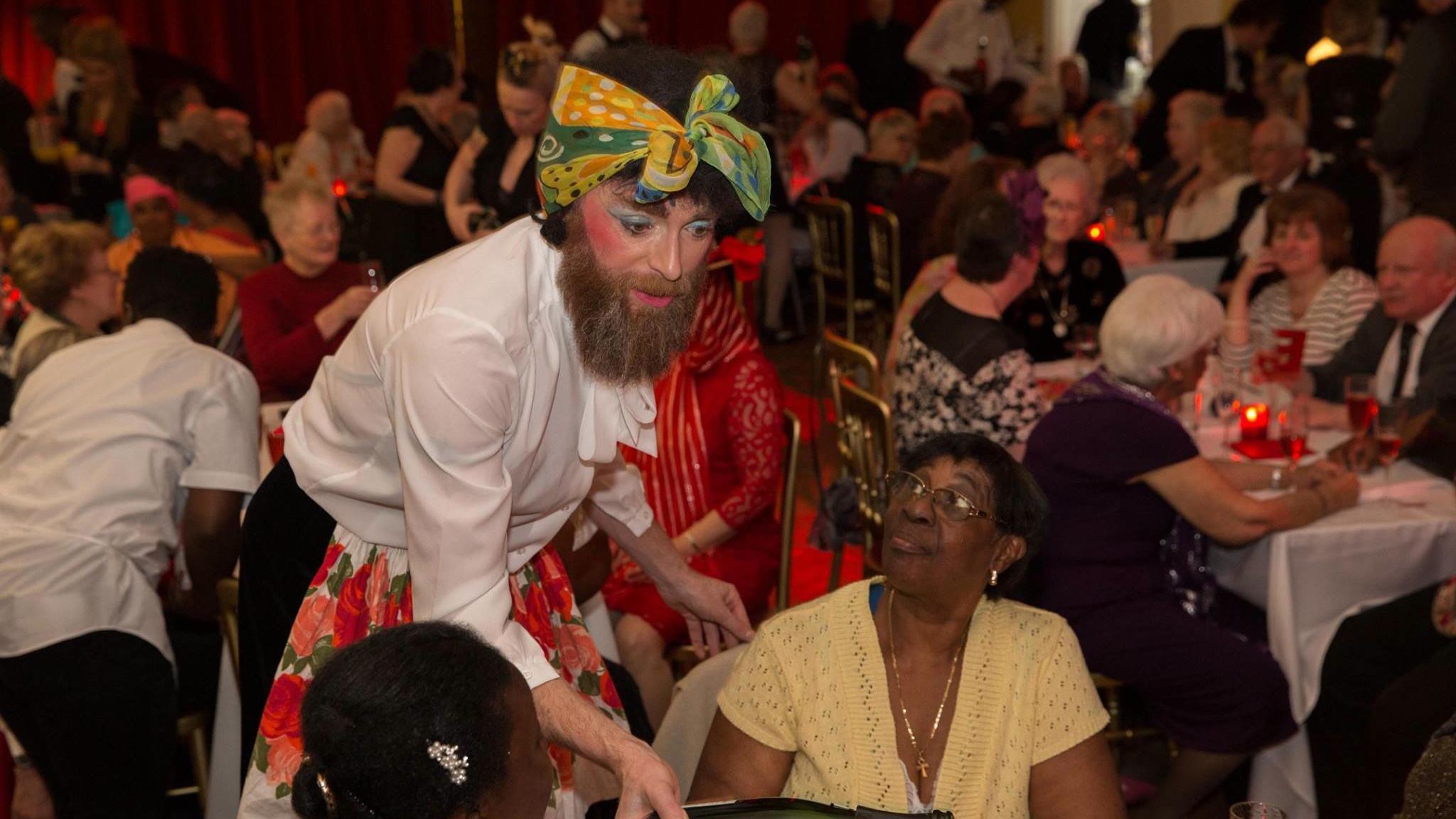 A waiter dressed in 1940s costume serving tea at a large party