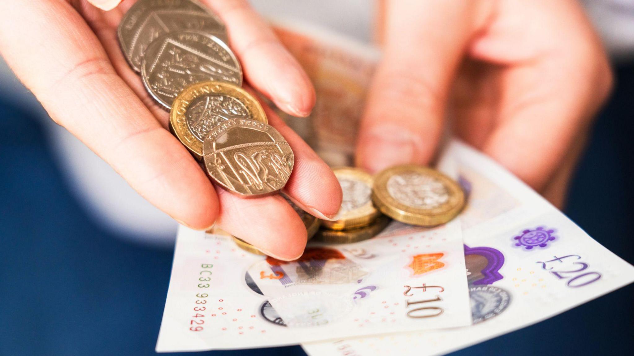 A stock image of notes and coins in an outstretched hand.