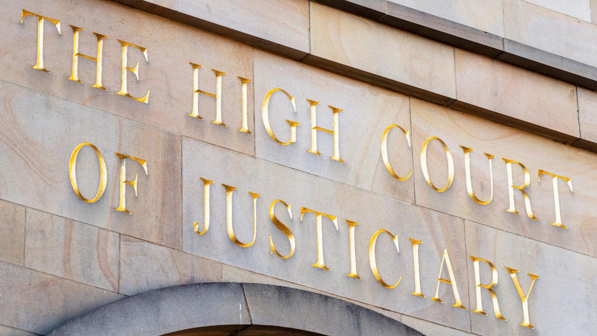 A wall with gold letters saying The High Court of Justiciary