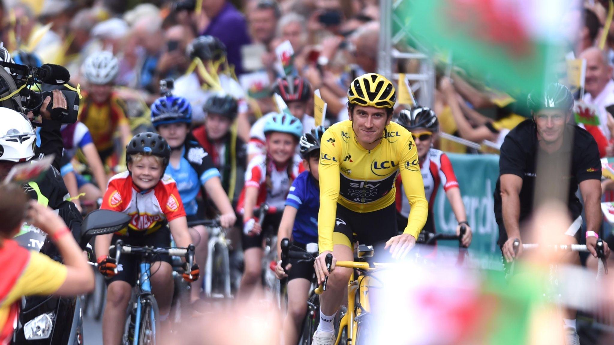 Geraint Thomas in a yellow jersey rides through the crowds along with youngsters