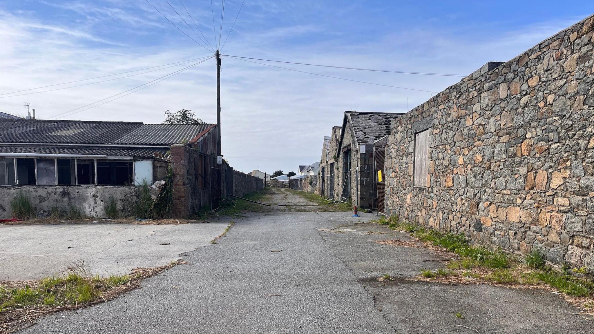 Leale's Yard. A road with a series of abandoned industrial buildings made out of granite and brick, with corrugated iron roofs.