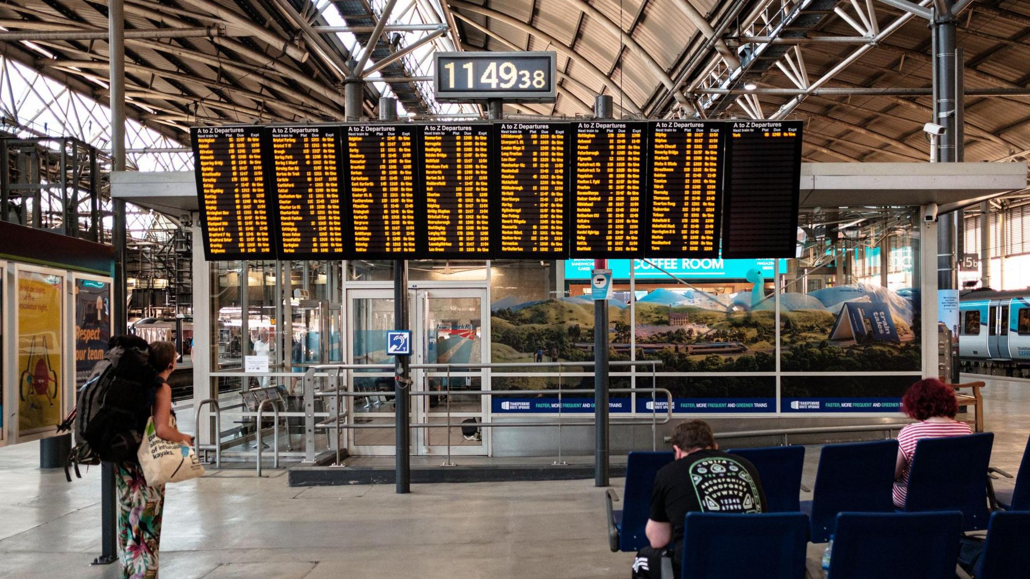 A large arrival and departure board displays train schedules and destinations in a train station.