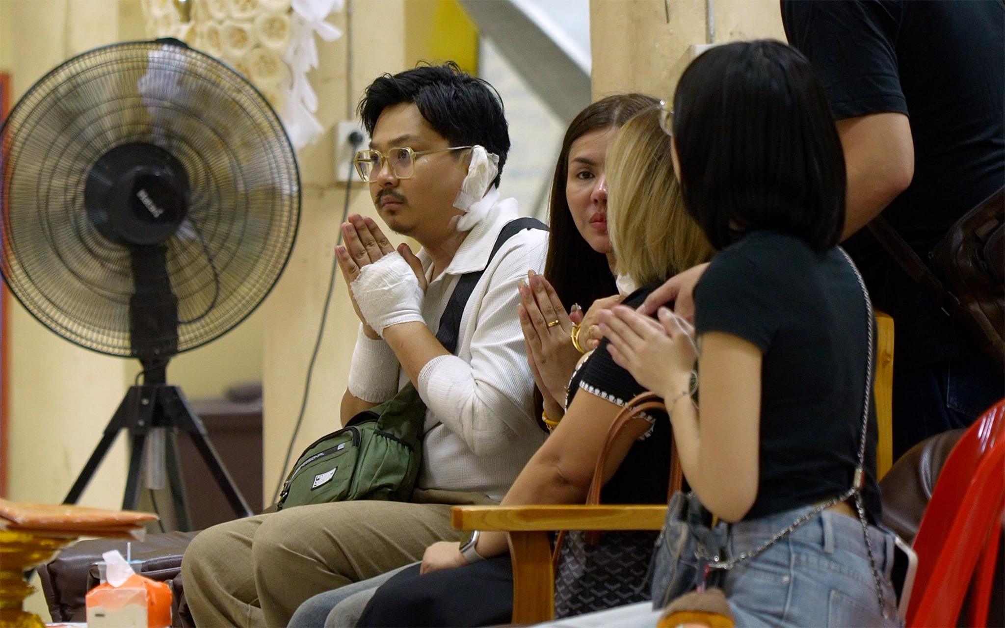 Athipat Wichan (left) and others clasp their hands together during a funeral ceremony