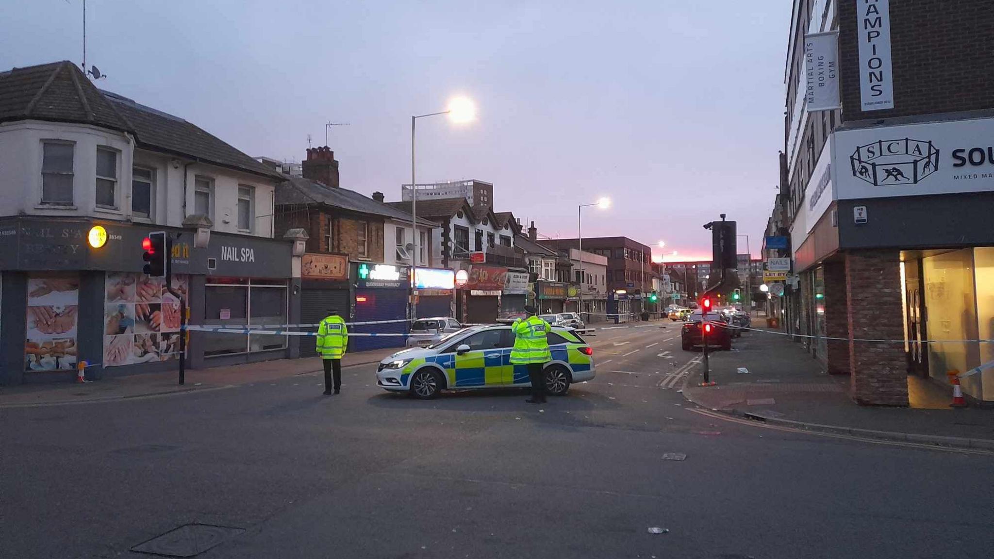 A photo of Southchurch Road in Southend-on-Sea following the incident. The road has been cordoned off with police tape. A police car can be seen within the cordon and there are two officers on the scene. 